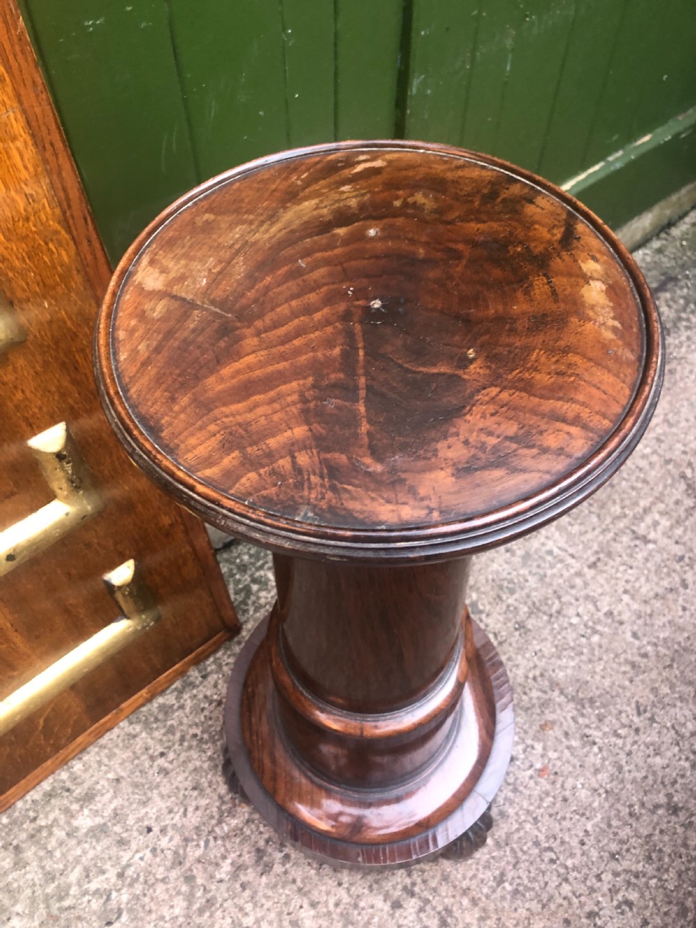 A dark brown turned rosewood columnar sculpture pedestal featuring a moulded top disc, architectural cylindrical shaft, and carved feet. View III