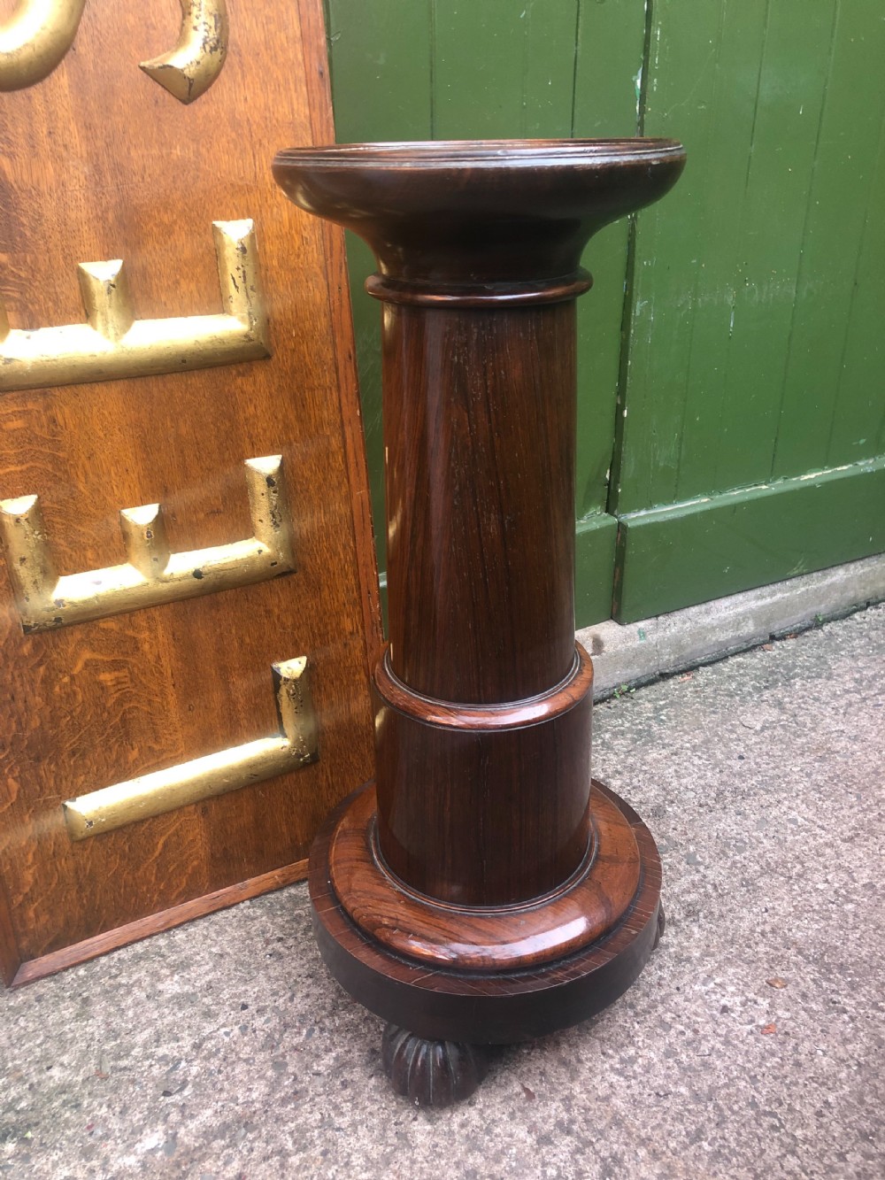 A dark brown turned rosewood columnar sculpture pedestal featuring a moulded top disc, architectural cylindrical shaft, and carved feet. View V