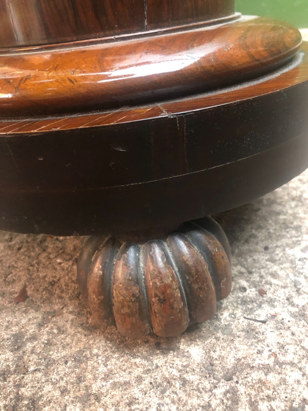 A dark brown turned rosewood columnar sculpture pedestal featuring a moulded top disc, architectural cylindrical shaft, and carved feet. View VI