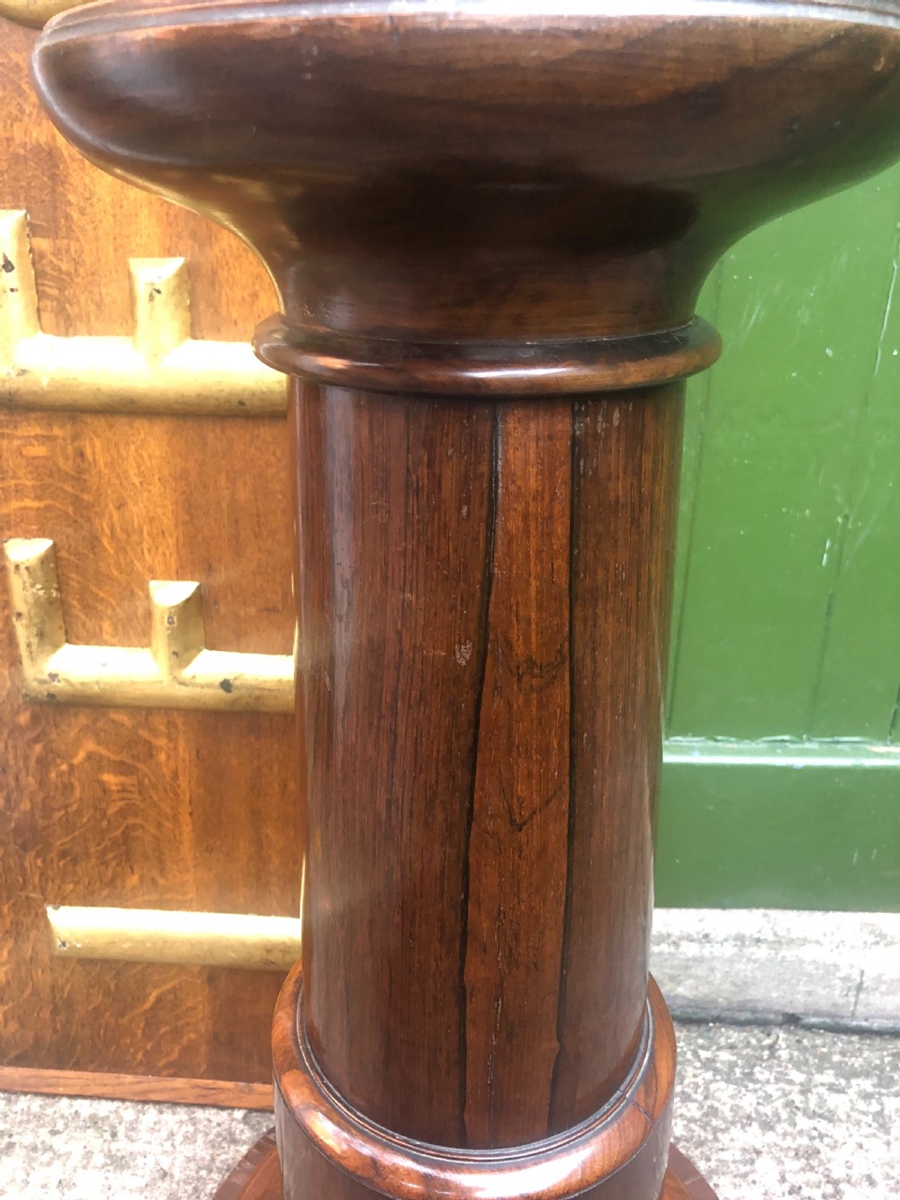 A dark brown turned rosewood columnar sculpture pedestal featuring a moulded top disc, architectural cylindrical shaft, and carved feet. View VIII