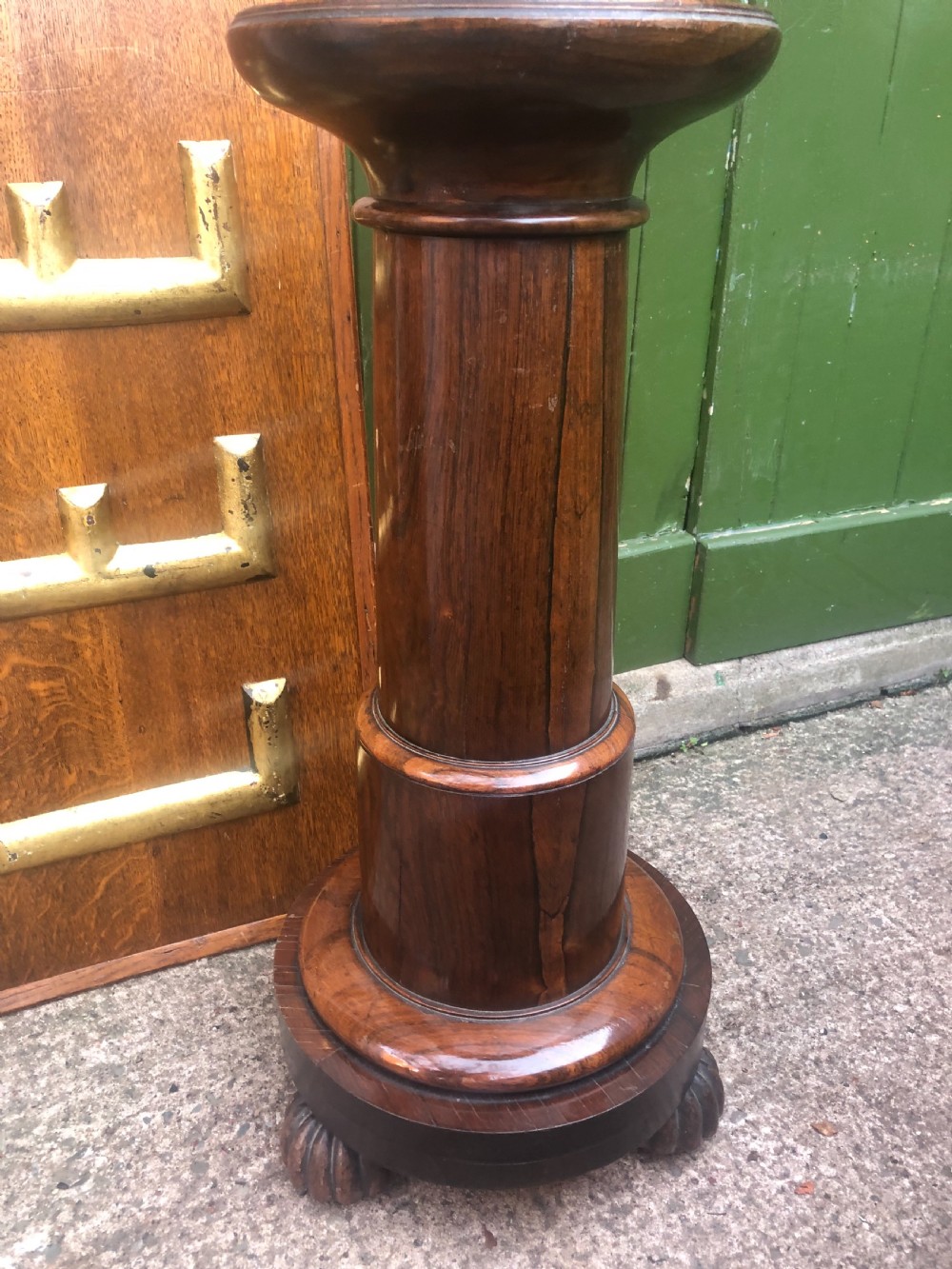A dark brown turned rosewood columnar sculpture pedestal featuring a moulded top disc, architectural cylindrical shaft, and carved feet. View IX