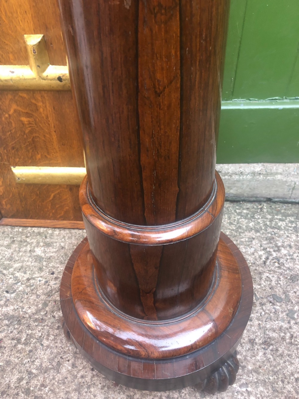 A dark brown turned rosewood columnar sculpture pedestal featuring a moulded top disc, architectural cylindrical shaft, and carved feet. View X