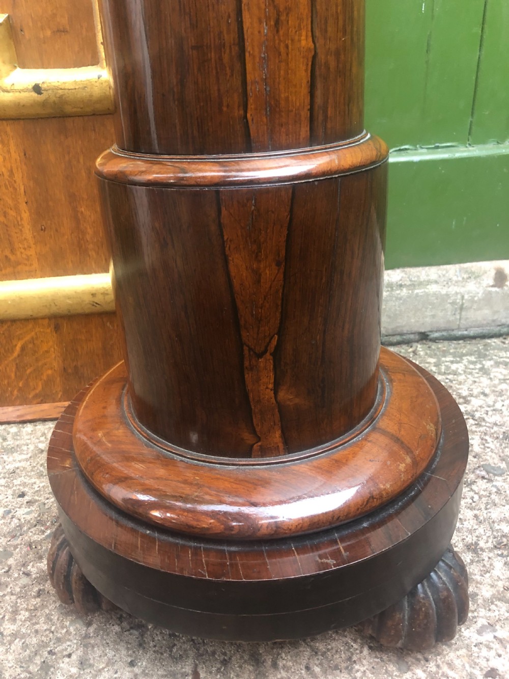 A dark brown turned rosewood columnar sculpture pedestal featuring a moulded top disc, architectural cylindrical shaft, and carved feet. View XI