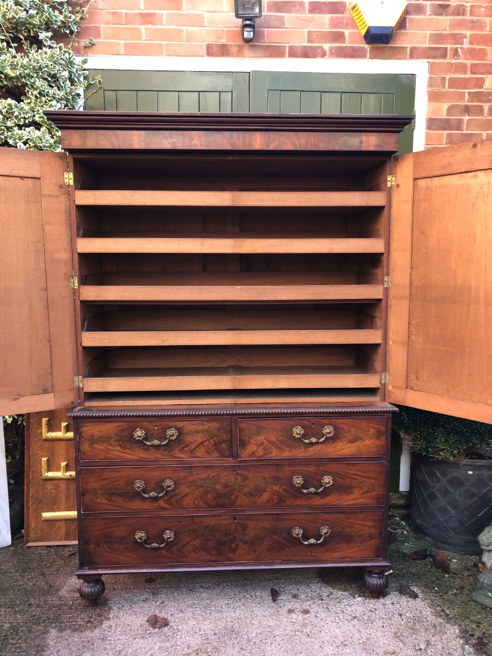 A William IV flame mahogany linen press featuring a double door upper cupboard with rope-twist side columns set above a lower chest of drawers with brass handles. View VIII