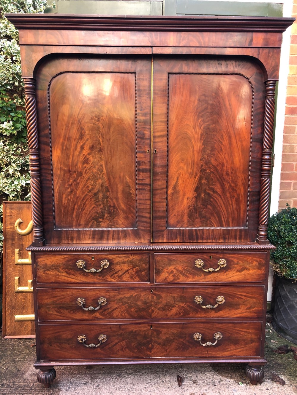 A William IV flame mahogany linen press featuring a double door upper cupboard with rope-twist side columns set above a lower chest of drawers with brass handles. View XIII