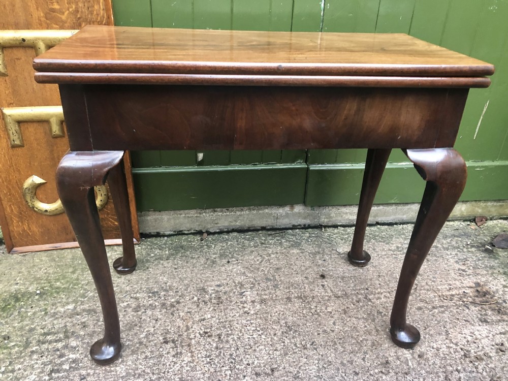 A mid-18th-century George II mahogany fold-over gaming table featuring elegant cabriole legs with pad feet.