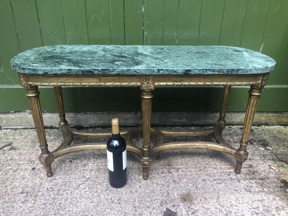 An early 20th-century French Louis XVI style low table with a green marble top, giltwood frame, fluted legs, and carved rosette details. View XVI
