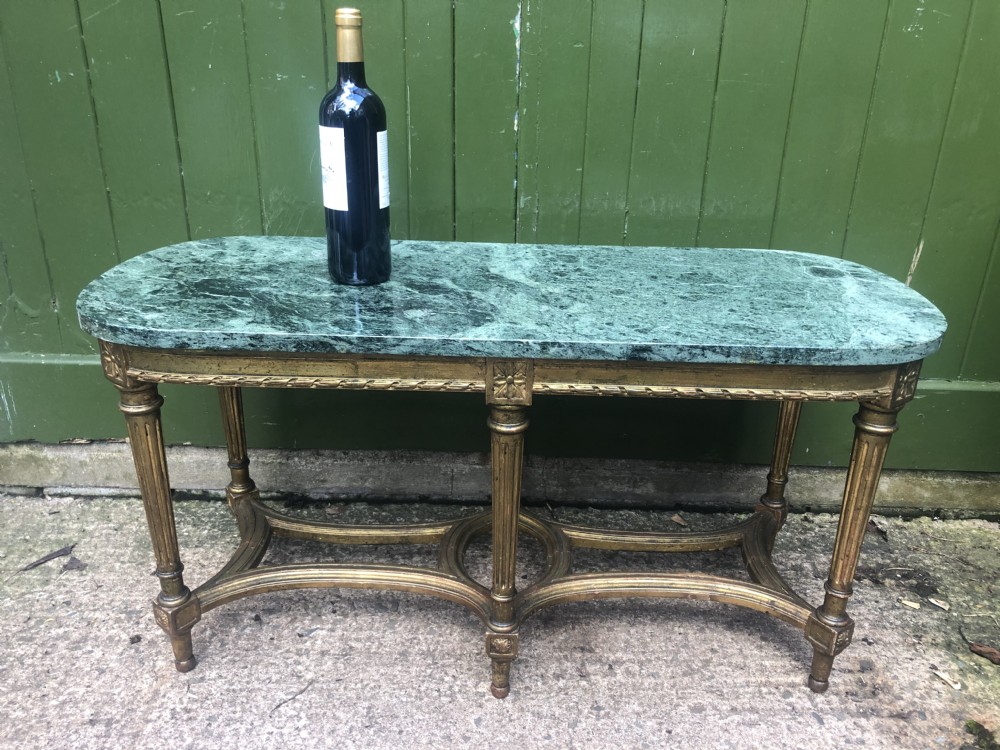 An early 20th-century French Louis XVI style low table with a green marble top, giltwood frame, fluted legs, and carved rosette details. View XVII