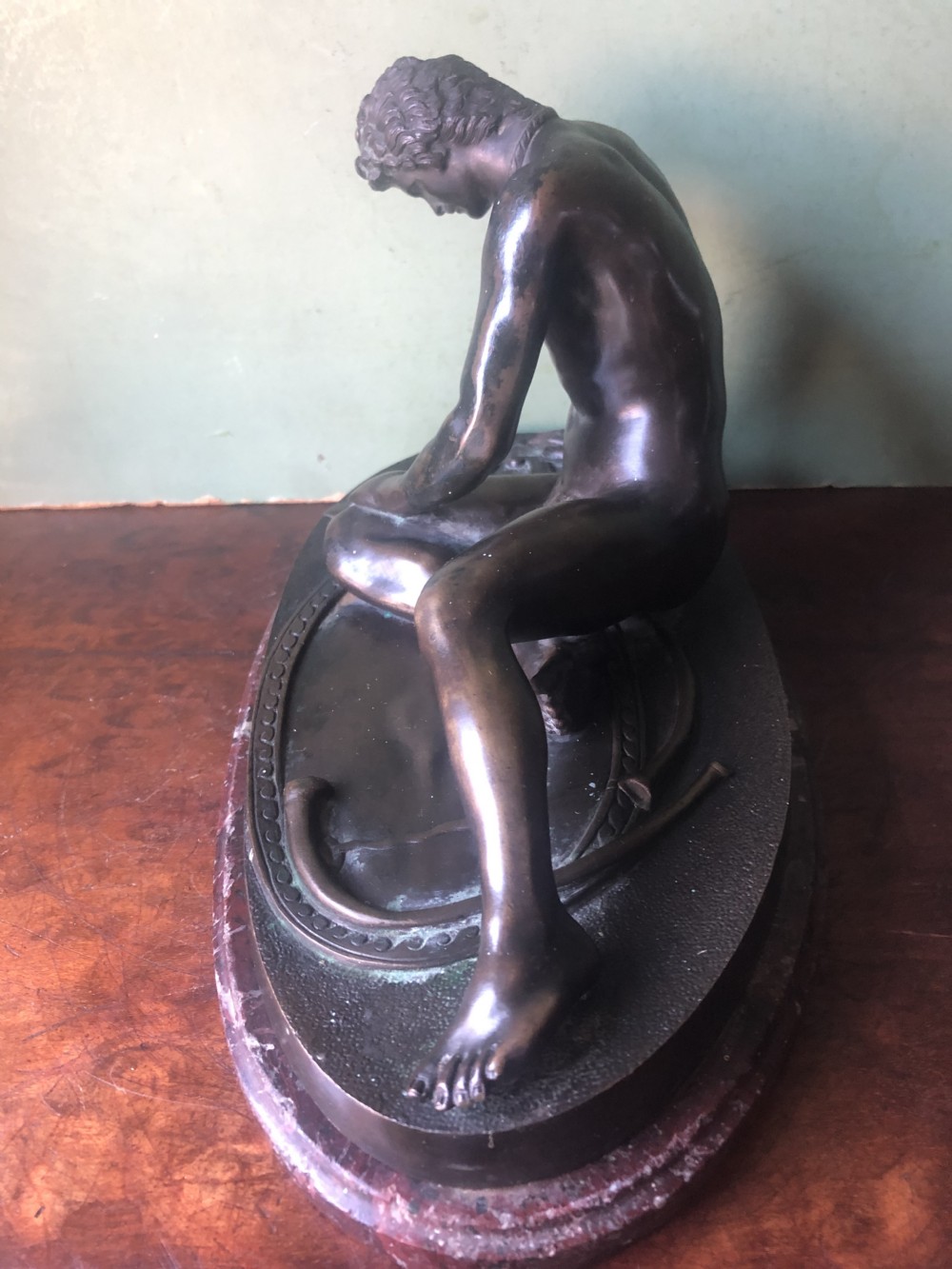 A late 19th-century dark bronze sculpture depicting a recumbent classical warrior mounted on an oval red marble base. View VIII