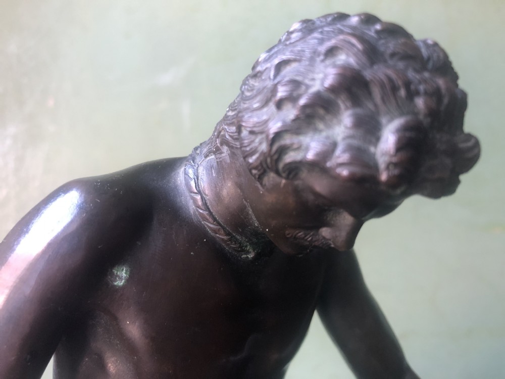 A late 19th-century dark bronze sculpture depicting a recumbent classical warrior mounted on an oval red marble base. View IX