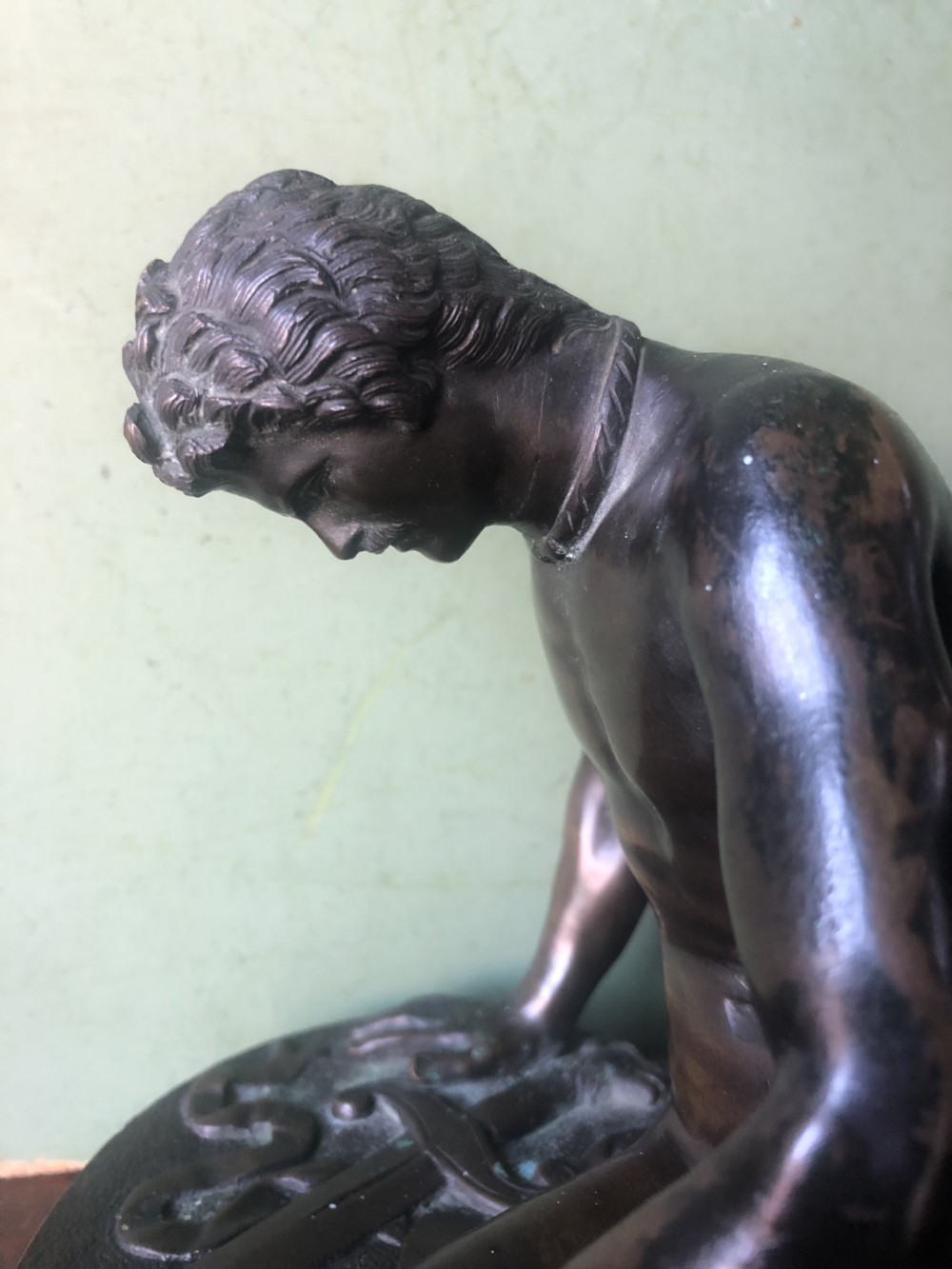 A late 19th-century dark bronze sculpture depicting a recumbent classical warrior mounted on an oval red marble base. View XIII