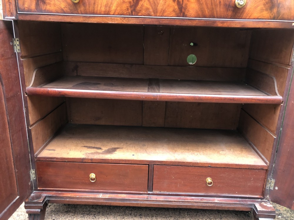 An early nineteenth-century flame mahogany side cabinet with arch-panelled double doors, top drawer, and brass fittings. View VII