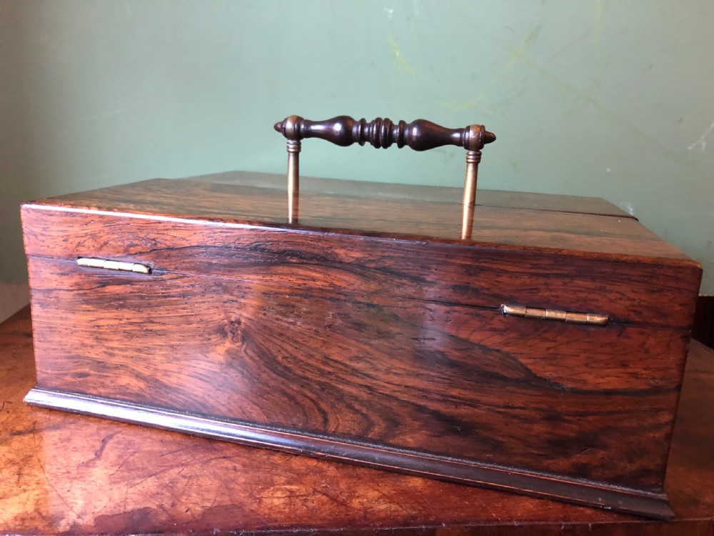 A dark rosewood rectangular desk tidy featuring a central turned wood and brass handle, hinged lids, and a moulded base.
