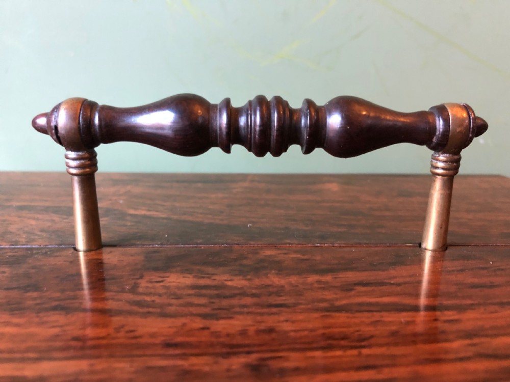 A dark rosewood rectangular desk tidy featuring a central turned wood and brass handle, hinged lids, and a moulded base. View X