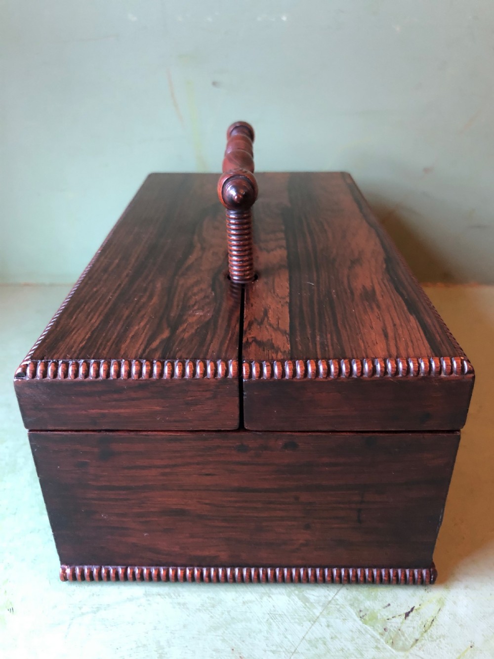 A dark rosewood rectangular desk tidy featuring a central turned wood and brass handle, hinged lids, and a moulded base. View XX