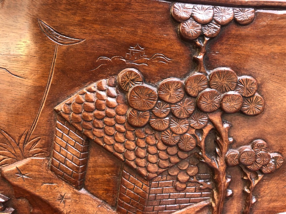 An antique Chinese dark hardwood hall bench featuring detailed relief carvings of bats, landscapes, and traditional character motifs on the backrest. View XII