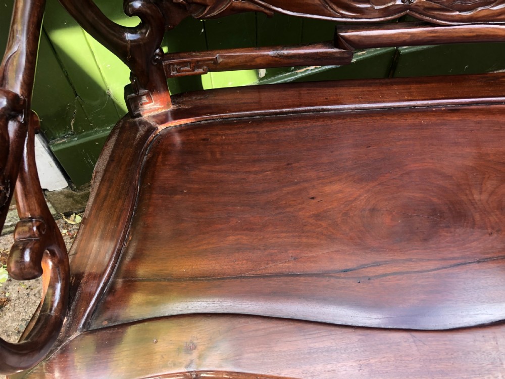 An antique Chinese dark hardwood hall bench featuring detailed relief carvings of bats, landscapes, and traditional character motifs on the backrest. View XIII