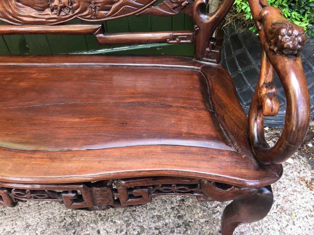An antique Chinese dark hardwood hall bench featuring detailed relief carvings of bats, landscapes, and traditional character motifs on the backrest. View XVI