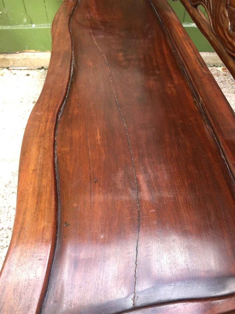 An antique Chinese dark hardwood hall bench featuring detailed relief carvings of bats, landscapes, and traditional character motifs on the backrest. View XVIII