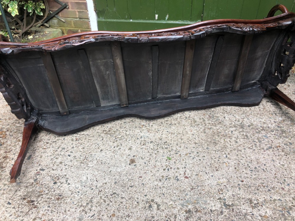 An antique Chinese dark hardwood hall bench featuring detailed relief carvings of bats, landscapes, and traditional character motifs on the backrest. View XXIII