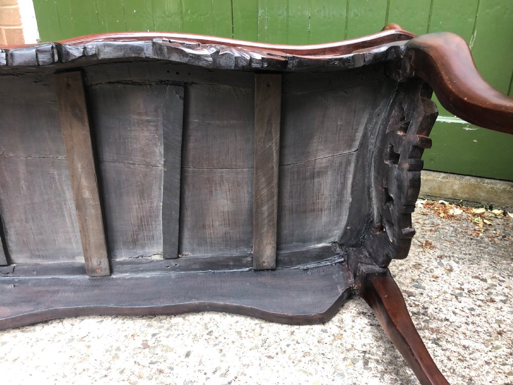 An antique Chinese dark hardwood hall bench featuring detailed relief carvings of bats, landscapes, and traditional character motifs on the backrest. View XXIV