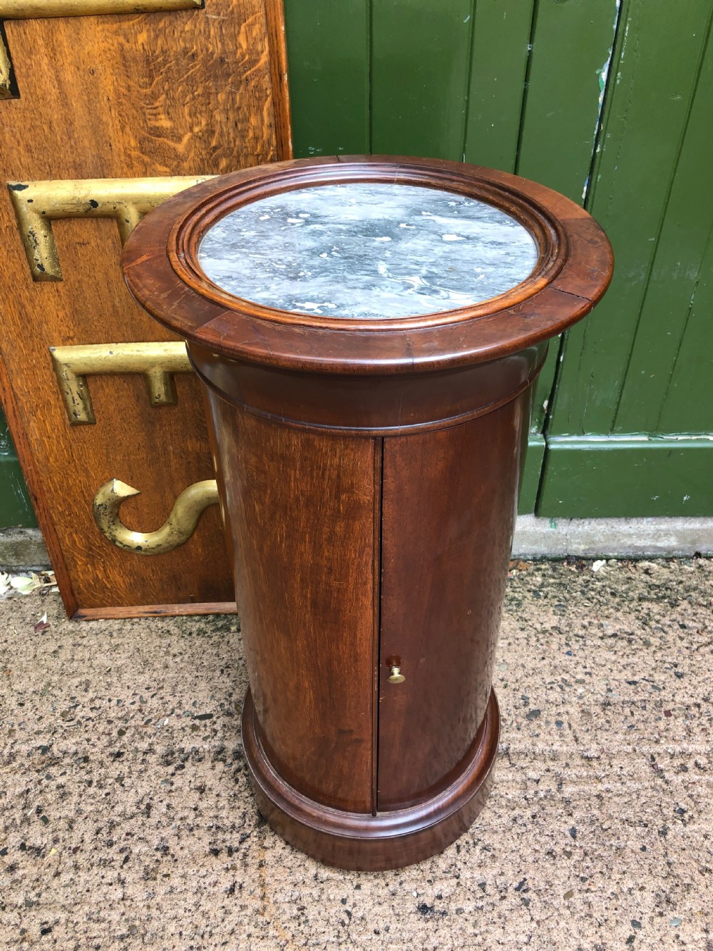 An early nineteenth-century French Empire mahogany cylindrical cupboard featuring an inset marble top, a single curved door with a small brass knob, and a plinth base. View II