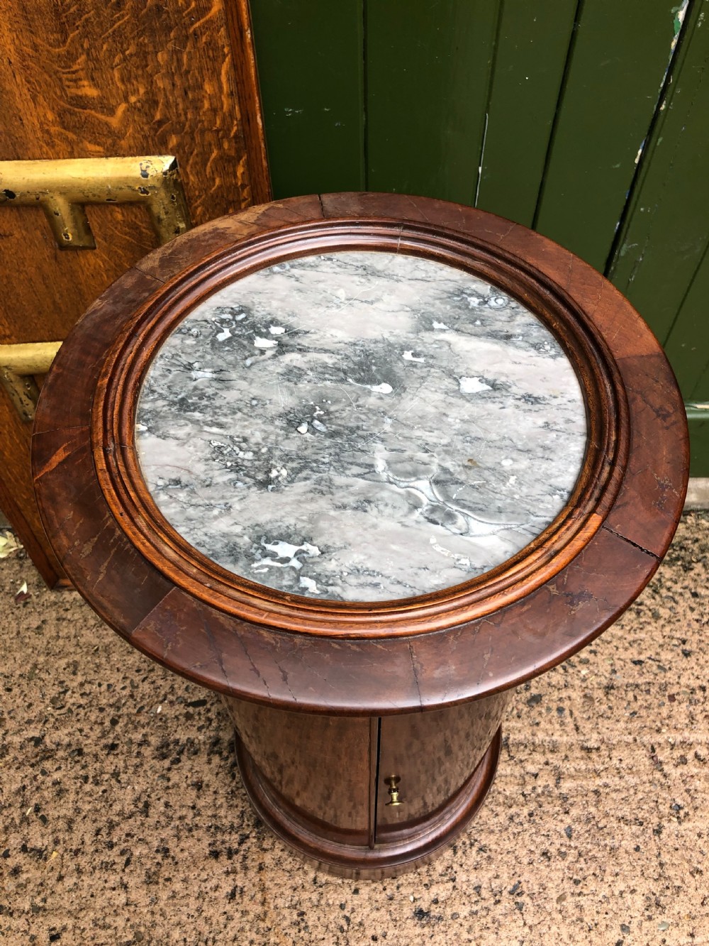 An early nineteenth-century French Empire mahogany cylindrical cupboard featuring an inset marble top, a single curved door with a small brass knob, and a plinth base. View III
