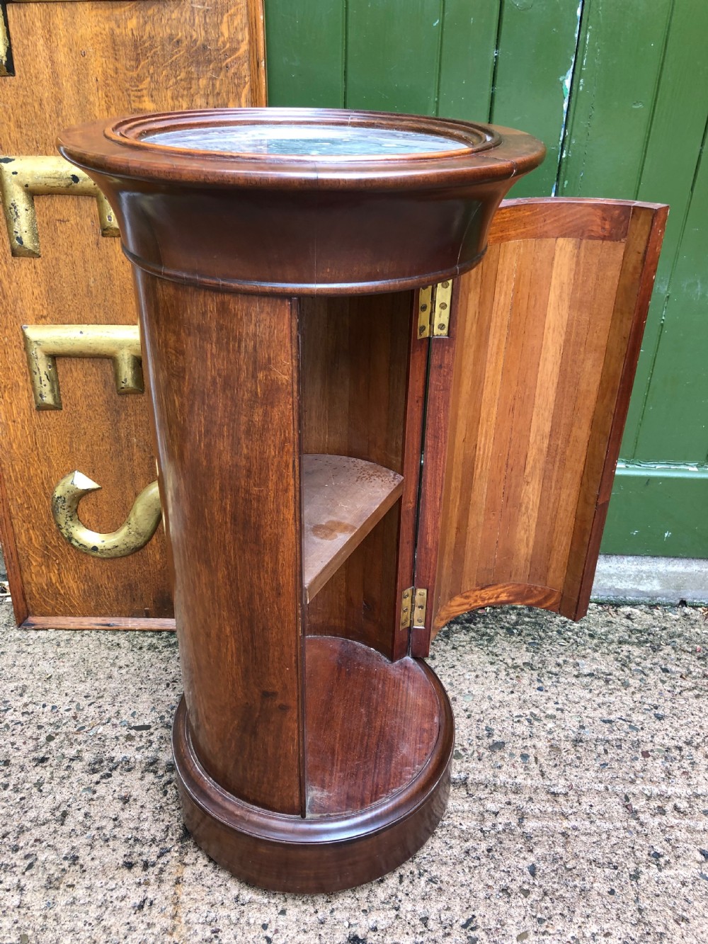An early nineteenth-century French Empire mahogany cylindrical cupboard featuring an inset marble top, a single curved door with a small brass knob, and a plinth base. View V