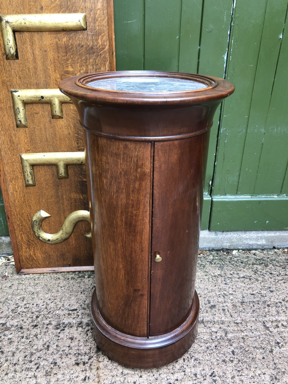 An early nineteenth-century French Empire mahogany cylindrical cupboard featuring an inset marble top, a single curved door with a small brass knob, and a plinth base. View XVI