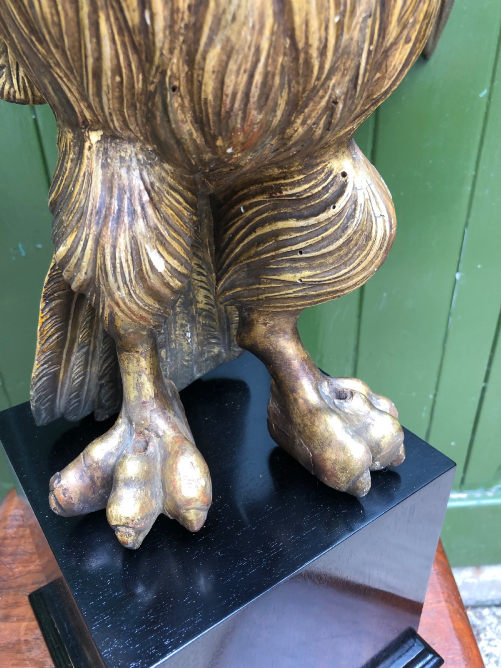 A carved giltwood swan sculpture with outstretched wings and a lowered head mounted on a black square pedestal. View XVIII