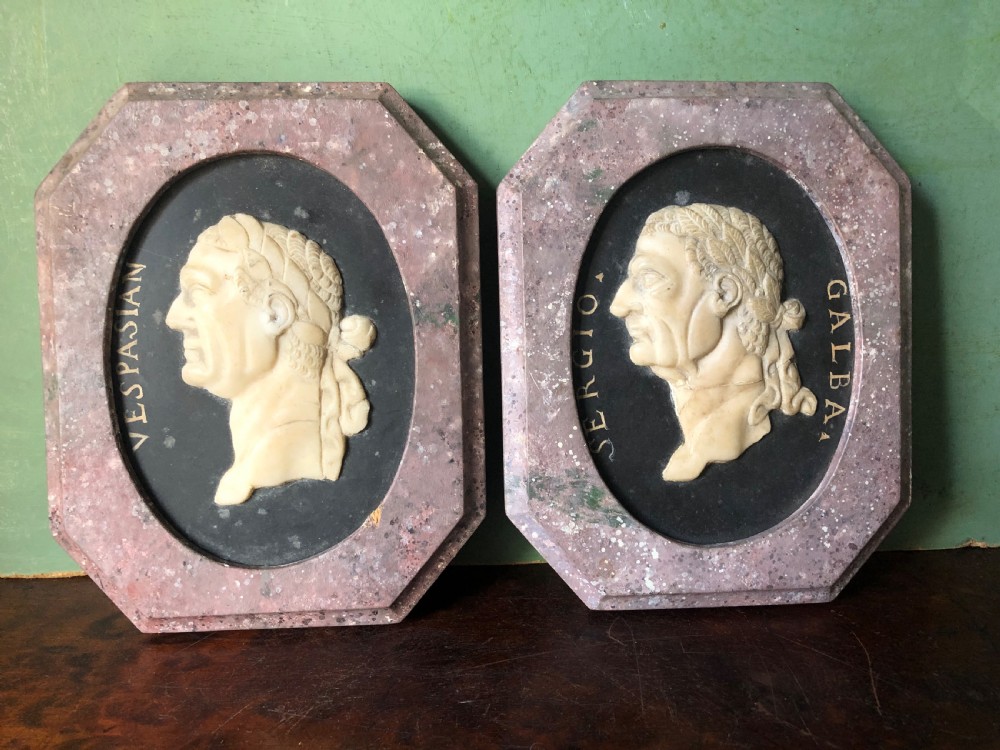 A pair of octagonal mottled pink marble plaques featuring carved off-white marble profile portraits of Roman emperors Vespasian and Galba set against black oval backgrounds. View II