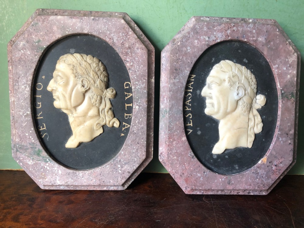 A pair of octagonal mottled pink marble plaques featuring carved off-white marble profile portraits of Roman emperors Vespasian and Galba set against black oval backgrounds. View III