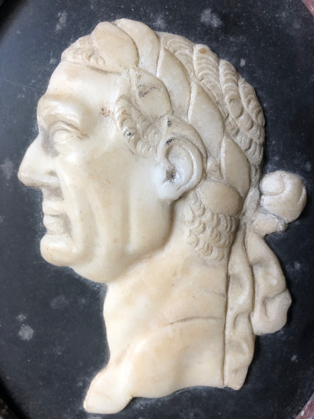 A pair of octagonal mottled pink marble plaques featuring carved off-white marble profile portraits of Roman emperors Vespasian and Galba set against black oval backgrounds. View VII