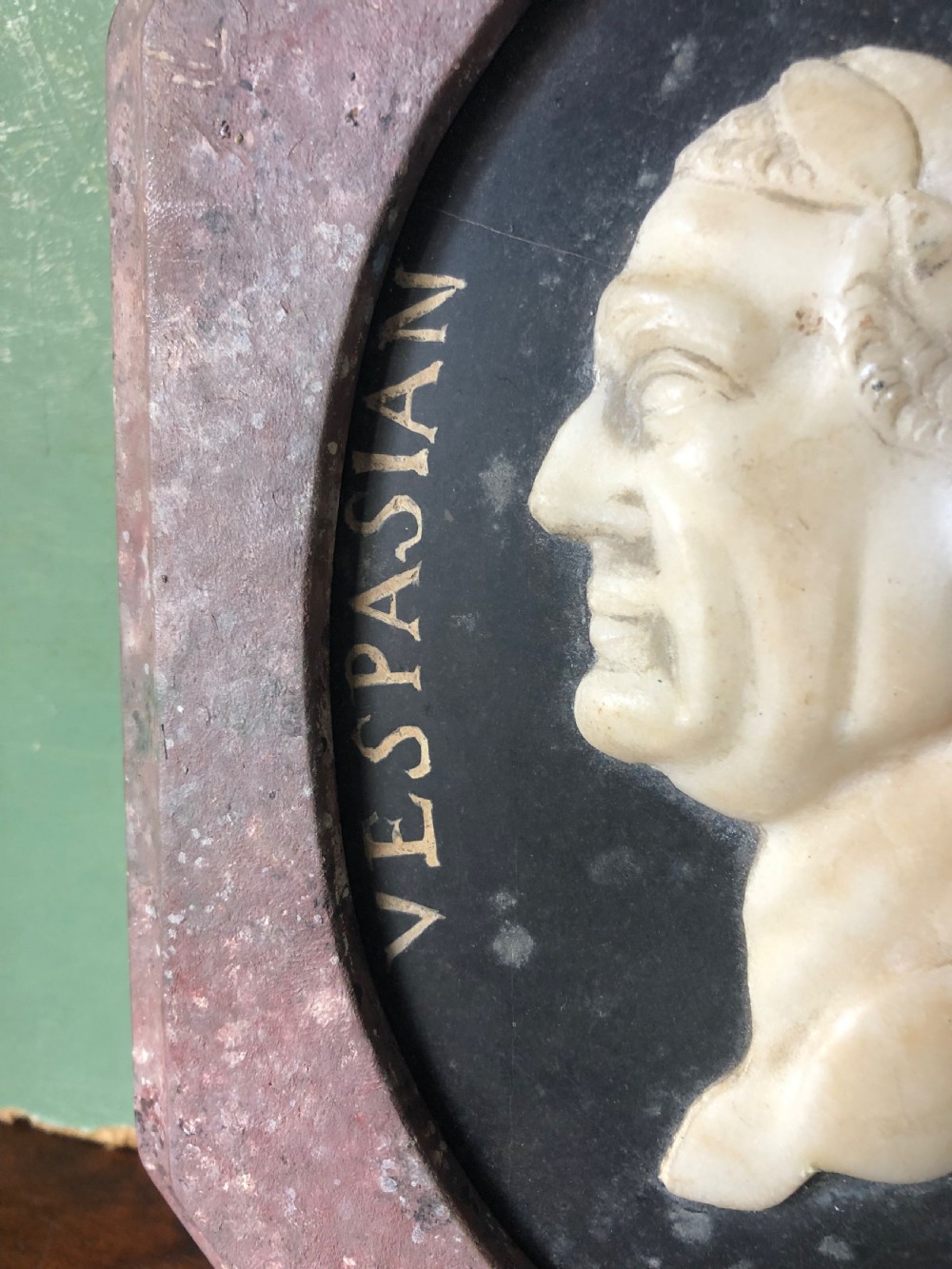 A pair of octagonal mottled pink marble plaques featuring carved off-white marble profile portraits of Roman emperors Vespasian and Galba set against black oval backgrounds. View VIII