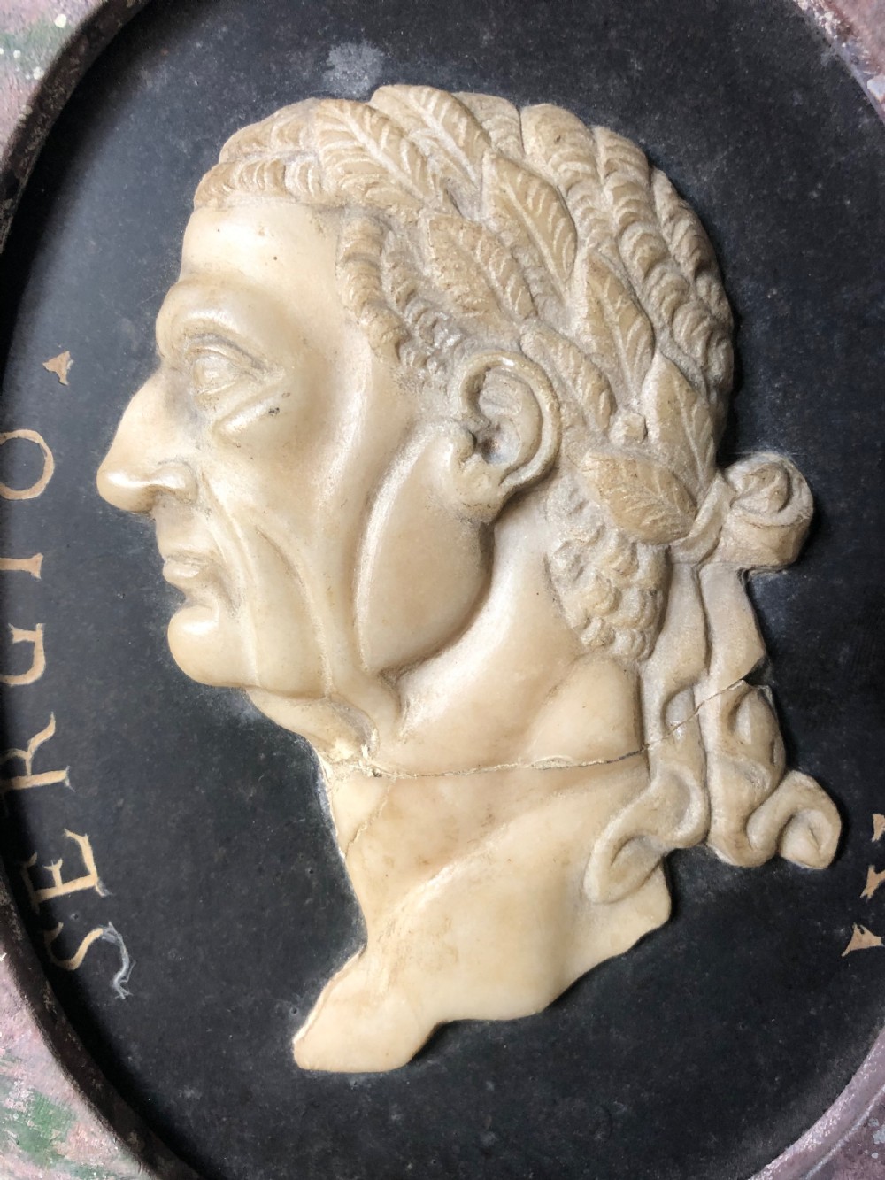 A pair of octagonal mottled pink marble plaques featuring carved off-white marble profile portraits of Roman emperors Vespasian and Galba set against black oval backgrounds. View IX