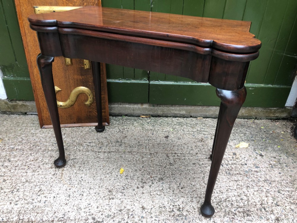 A mid-18th-century George II mahogany fold-over card table featuring slender cabriole legs terminating in pad feet and a shaped top. View X