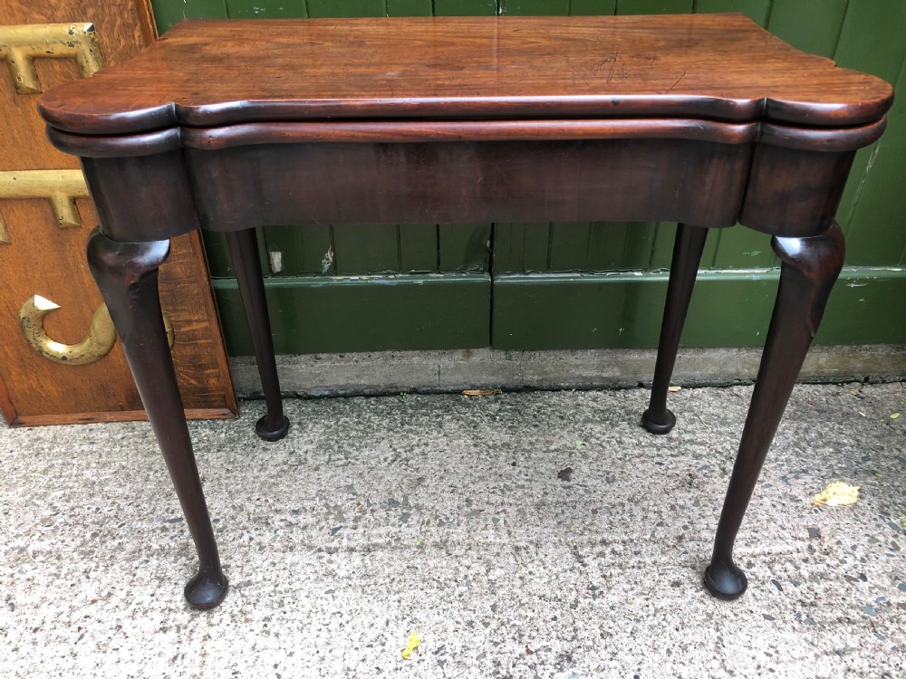 A mid-18th-century George II mahogany fold-over card table featuring slender cabriole legs terminating in pad feet and a shaped top. View XVIII