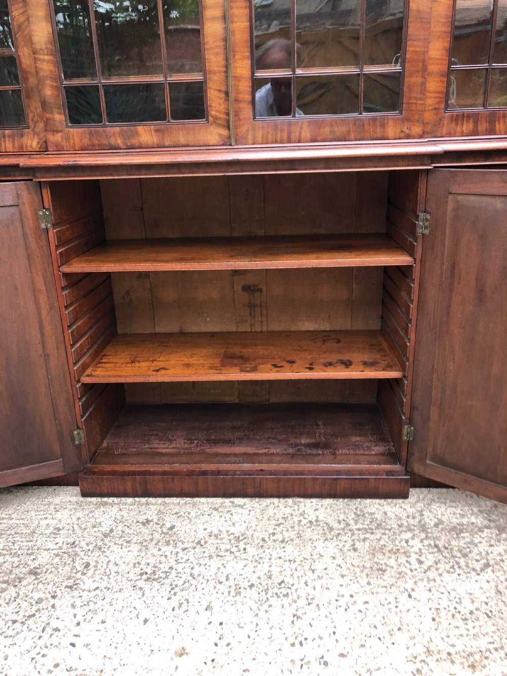 An early 19th-century George IV flame mahogany breakfront library bookcase featuring four upper glazed doors with astragal glazing bars above four fielded panel lower cupboards. View VIII