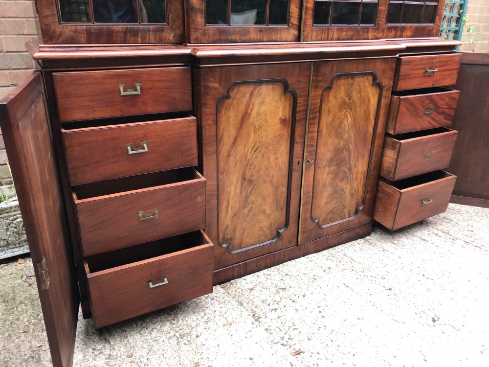 An early 19th-century George IV flame mahogany breakfront library bookcase featuring four upper glazed doors with astragal glazing bars above four fielded panel lower cupboards. View XXXI