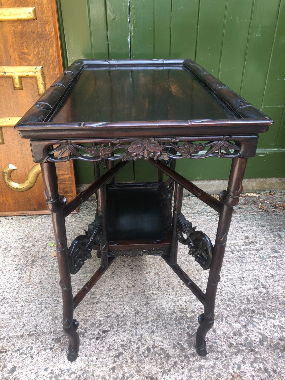 A late Qing dynasty dark carved hardwood tray table featuring faux-bamboo legs, carved foliage aprons, and a lower tier shelf. View IV