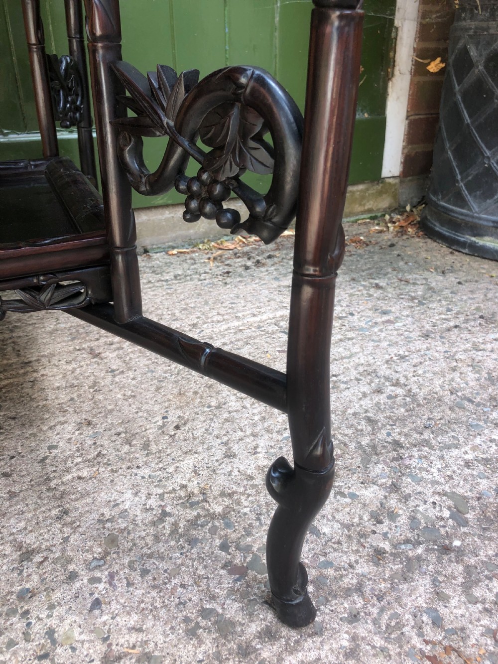 A late Qing dynasty dark carved hardwood tray table featuring faux-bamboo legs, carved foliage aprons, and a lower tier shelf. View V