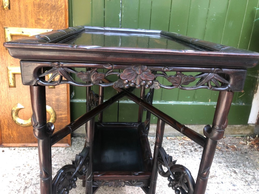 A late Qing dynasty dark carved hardwood tray table featuring faux-bamboo legs, carved foliage aprons, and a lower tier shelf. View VII