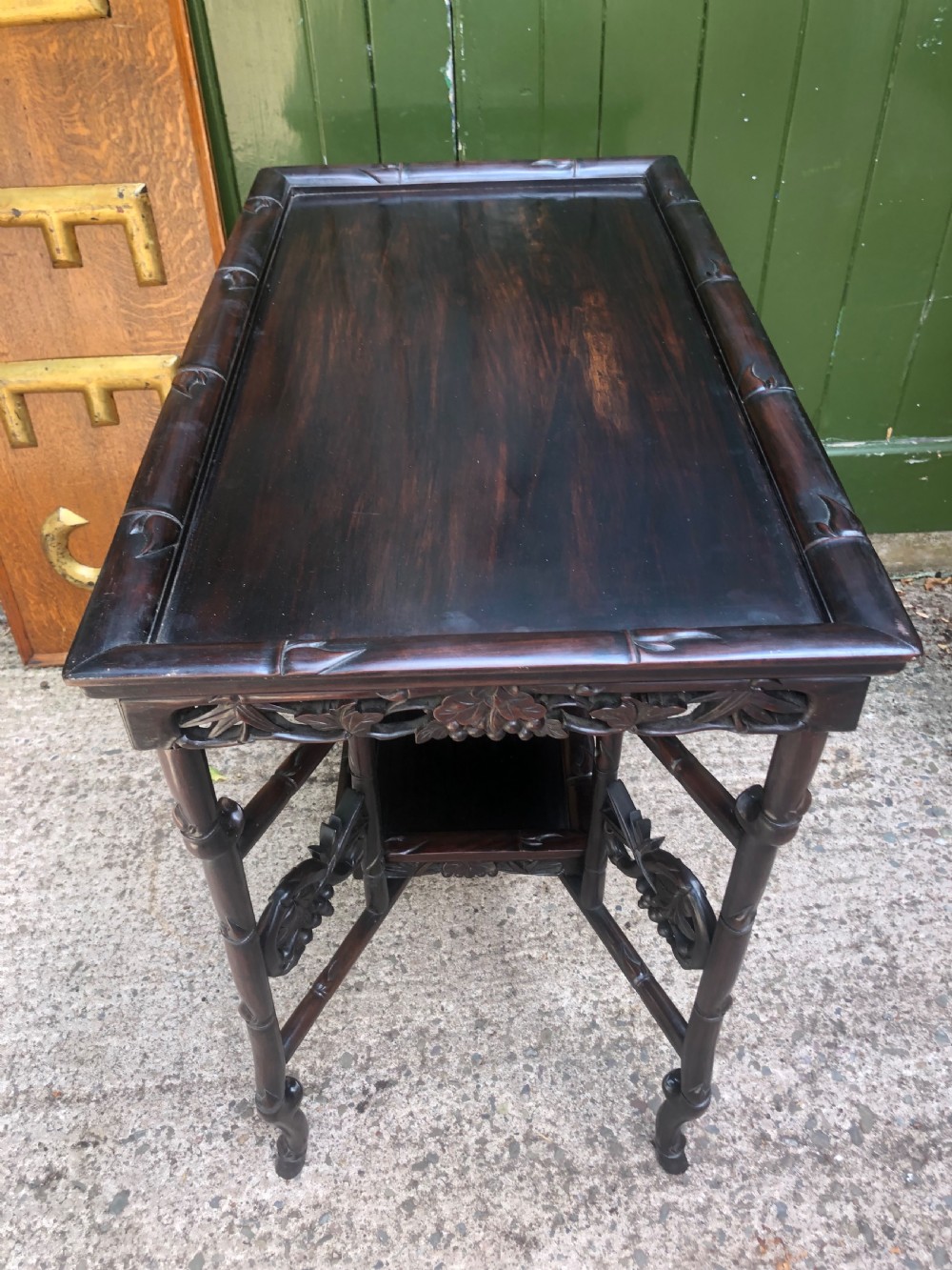 A late Qing dynasty dark carved hardwood tray table featuring faux-bamboo legs, carved foliage aprons, and a lower tier shelf. View IX