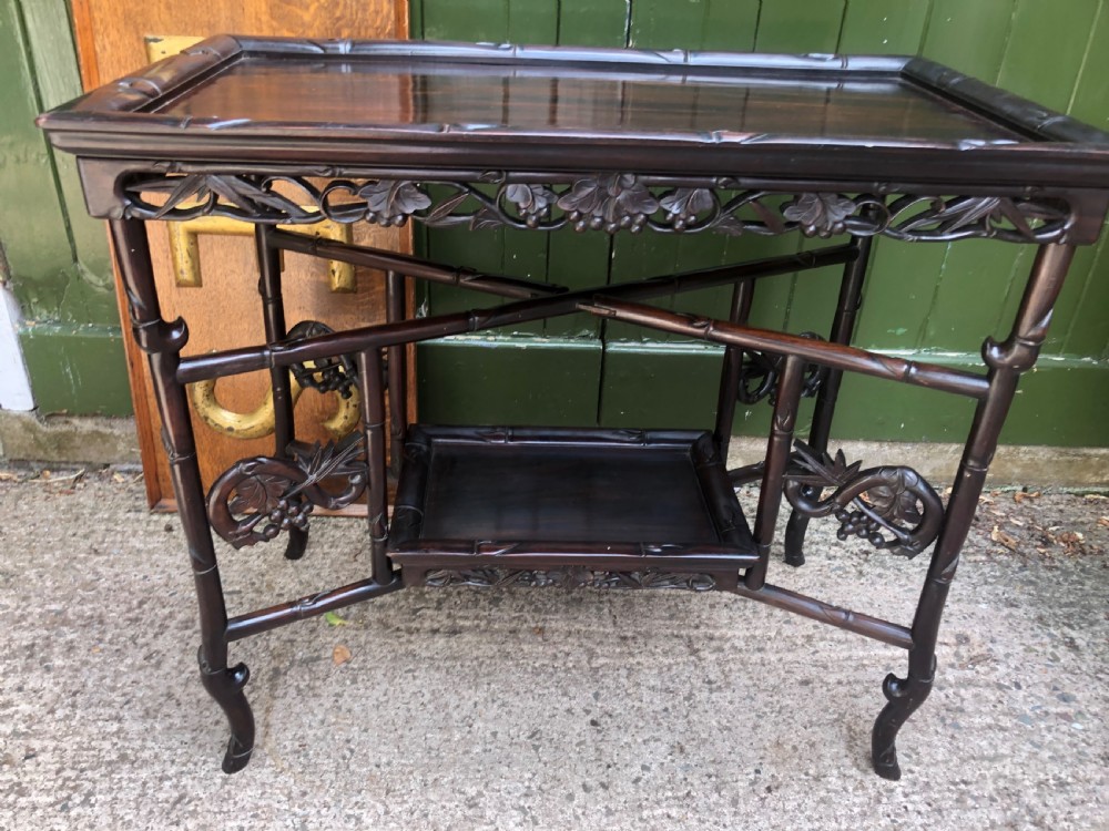 A late Qing dynasty dark carved hardwood tray table featuring faux-bamboo legs, carved foliage aprons, and a lower tier shelf. View XI