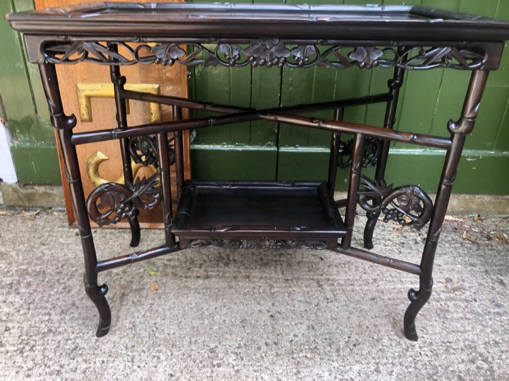A late Qing dynasty dark carved hardwood tray table featuring faux-bamboo legs, carved foliage aprons, and a lower tier shelf. View XIII