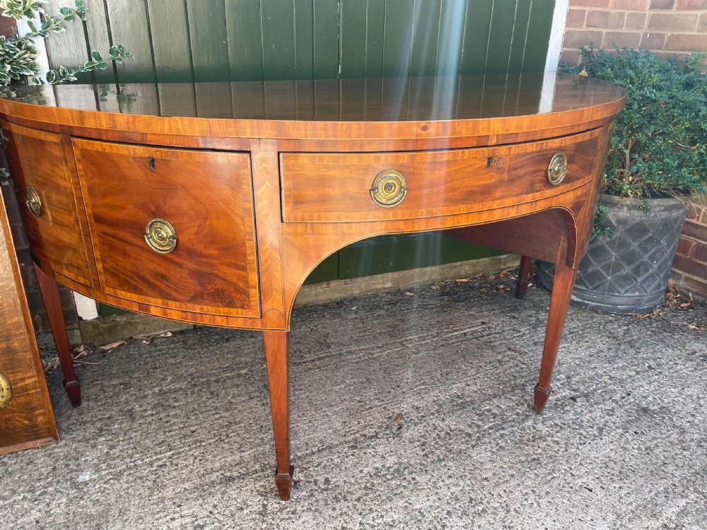 A late 18th-century George III mahogany demi-lune sideboard featuring inlaid stringing, a central drawer, curved side doors, and tapered square legs. View V