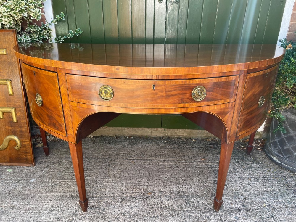 A late 18th-century George III mahogany demi-lune sideboard featuring inlaid stringing, a central drawer, curved side doors, and tapered square legs. View XIII