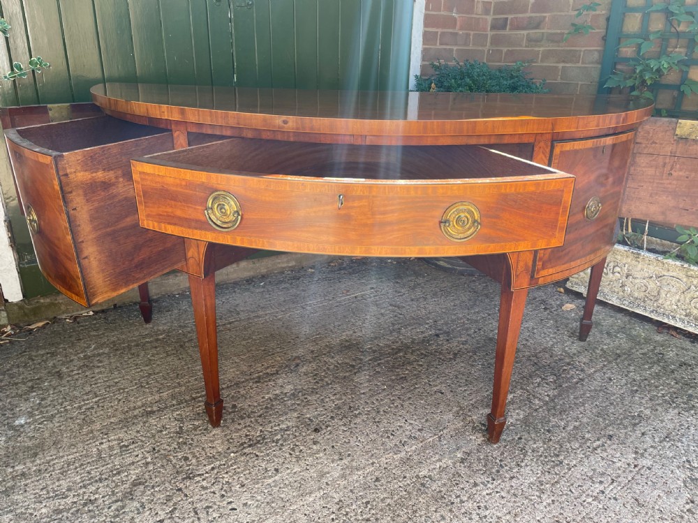 A late 18th-century George III mahogany demi-lune sideboard featuring inlaid stringing, a central drawer, curved side doors, and tapered square legs. View XIV