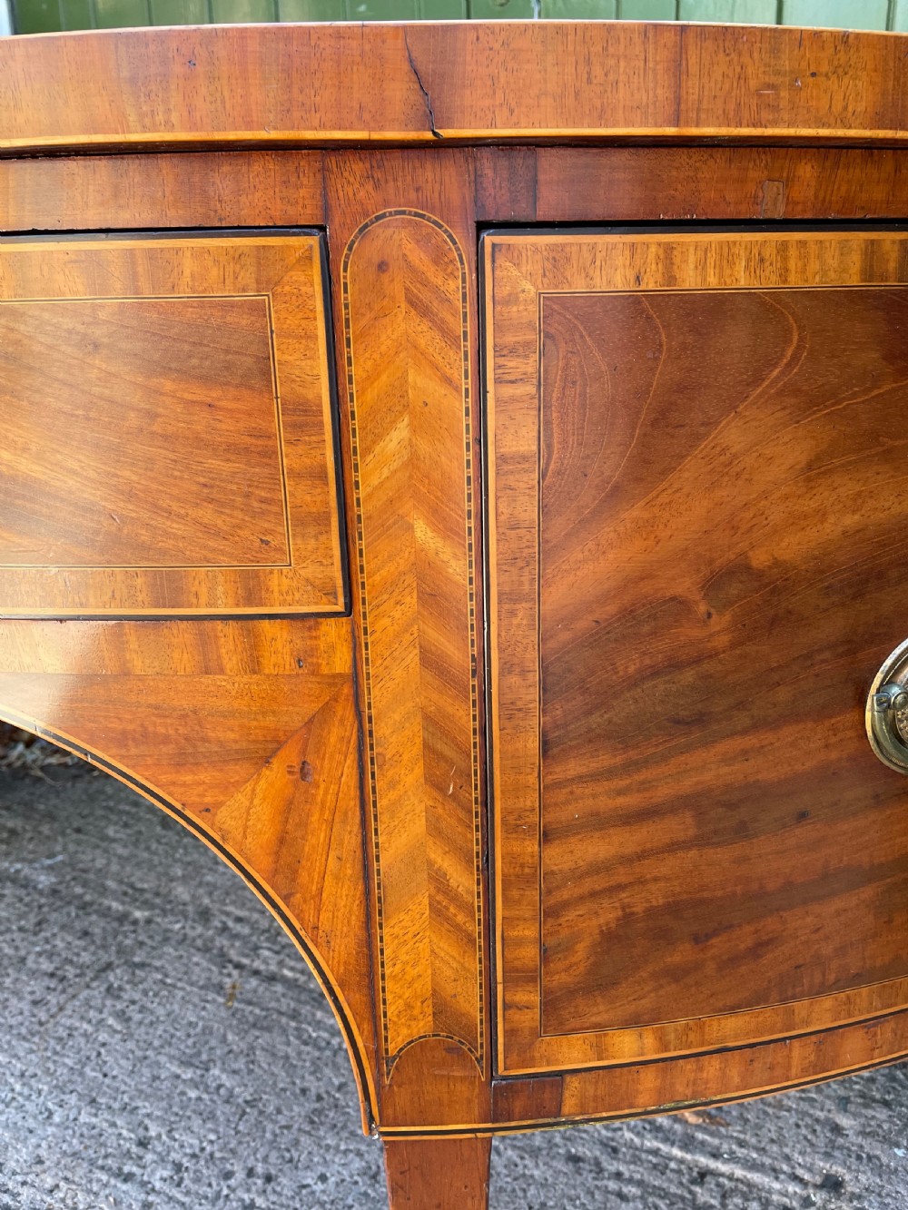 A late 18th-century George III mahogany demi-lune sideboard featuring inlaid stringing, a central drawer, curved side doors, and tapered square legs. View XXI