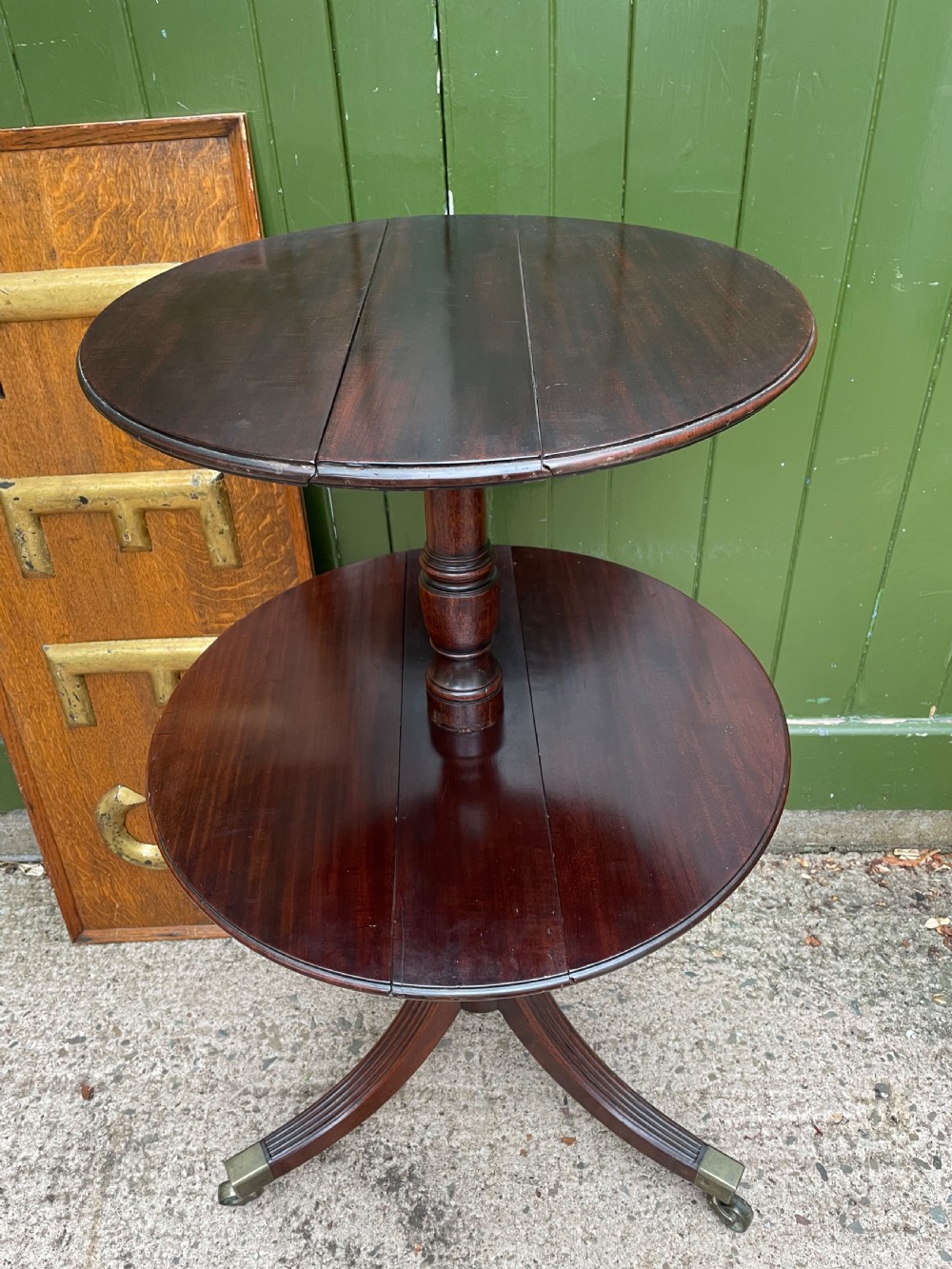 A late eighteenth-century George III mahogany two-tiered dumb waiter featuring drop-leaf circular shelves and a turned column on a tripod base with brass castors. View II
